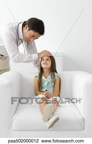Male doctor feeling young patient's forehead, girl sitting on armchair View Large Photo Image Stock Image - Male doctor feeling young patient's forehead, girl sitting on armchair. Fotosearch