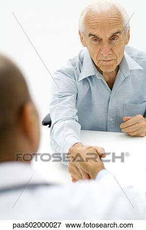 Senior man shaking younger man's hand, over the shoulder view View Large Photo Image Stock Photo - Senior man shaking younger man's hand, over the shoulder view. Fotosearch
