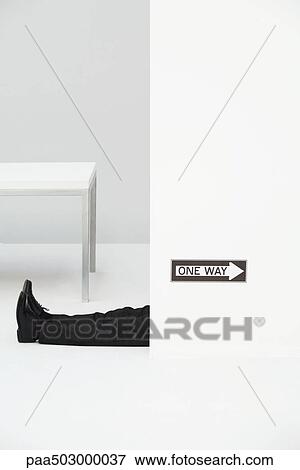 Businessman lying on the ground in office, "one way" sign pointing in opposite direction View Large Photo Image Stock Photo - Businessman lying on the ground in office, "one way" sign pointing in opposite direction. Fotosearch