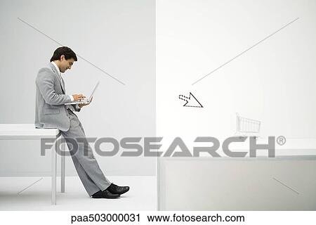 Businessman sitting on desk, shopping online, shopping cart and cursor in foreground View Large Photo Image Stock Image - Businessman sitting on desk, shopping online, shopping cart and cursor in foreground. Fotosearch