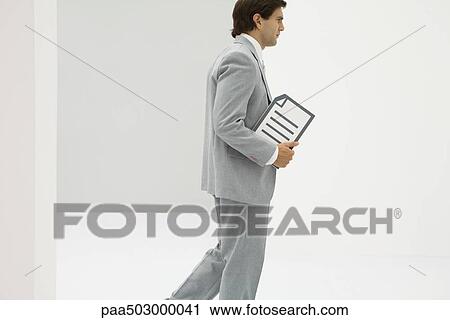 Businessman walking, carrying document, side view View Large Photo Image Stock Image - Businessman walking, carrying document, side view. Fotosearch