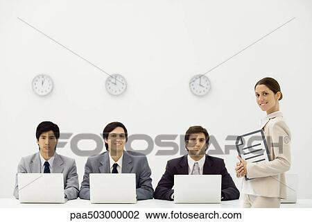Professional men sitting with laptop computers beneath wall clocks, female supervisor smiling at camera View Large Photo Image Stock Image - Professional men sitting with laptop computers beneath wall clocks, female supervisor smiling at camera. Fotosearch