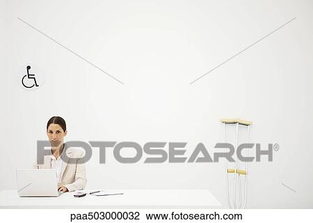 Professional woman working in office, smiling at camera, crutches leaning against wall nearby View Large Photo Image Stock Image - Professional woman working in office, smiling at camera, crutches leaning against wall nearby. Fotosearch