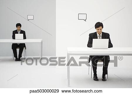 Young Professionals Sitting At Desks Using Laptops Blank Word