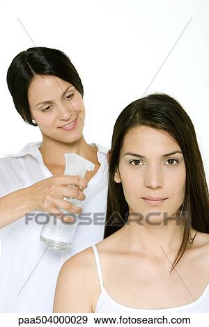 Hair stylist using spray bottle to moisten a woman's hair View Large Photo Image Stock Photo - Hair stylist using spray bottle to moisten a woman's hair. Fotosearch