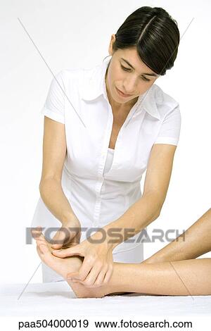Woman giving a foot massage, cropped view of woman's legs View Large Photo Image Stock Photo - Woman giving a foot massage, cropped view of woman's legs. Fotosearch
