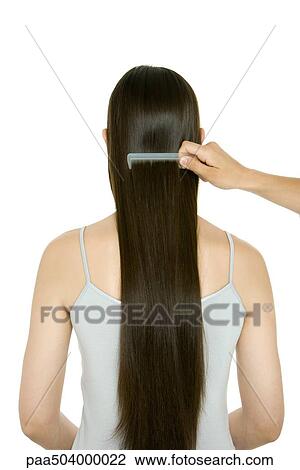 Stock Image - Woman having her long hair combed, rear view. Fotosearch