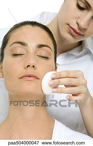 Stock Photo - Woman having her make-up removed by a beautician with cotton pad. Fotosearch