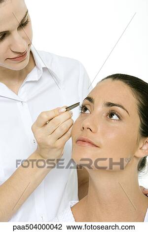 Woman looking up, beautician using tweezers to remove an eyelash View Large Photo Image Stock Image - Woman looking up, beautician using tweezers to remove an eyelash. Fotosearch