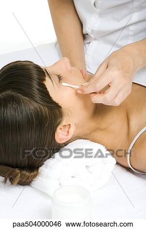 Woman lying on back, beautician rubbing cotton swab under her eye View Large Photo Image Stock Photograph - Woman lying on back, beautician rubbing cotton swab under her eye. Fotosearch