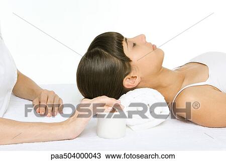 Woman lying on back with eyes closed, cropped view of beautician's hand preparing to apply moisturizer View Large Photo Image Stock Image - Woman lying on back with eyes closed, cropped view of beautician's hand preparing to apply moisturizer. Fotosearch