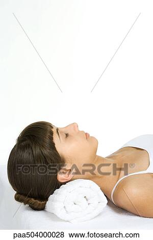 Woman lying on back with eyes closed, using towel as a pillow, cropped view View Large Photo Image Stock Photo - Woman lying on back with eyes closed, using towel as a pillow, cropped view. Fotosearch