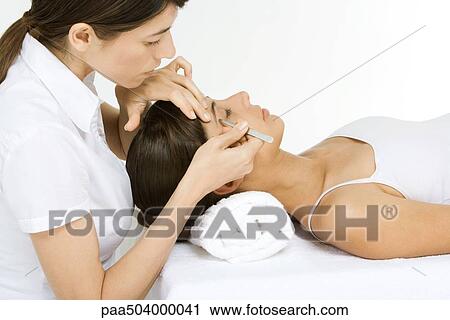 Woman lying on her back having her eyebrows plucked by a beautician View Large Photo Image Stock Image - Woman lying on her back having her eyebrows plucked by a beautician. Fotosearch