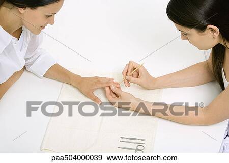 Woman receiving manicure, looking down at hand, cropped view View Large Photo Image Stock Photo - Woman receiving manicure, looking down at hand, cropped view. Fotosearch