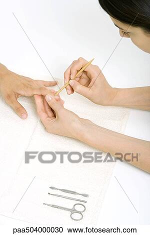 Woman using a cuticle pusher to give a manicure View Large Photo Image Stock Image - Woman using a cuticle pusher to give a manicure. Fotosearch