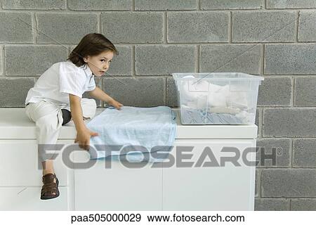 Little boy folding laundry, sitting on counter View Large Photo Image Stock Photo - Little boy folding laundry, sitting on counter. Fotosearch