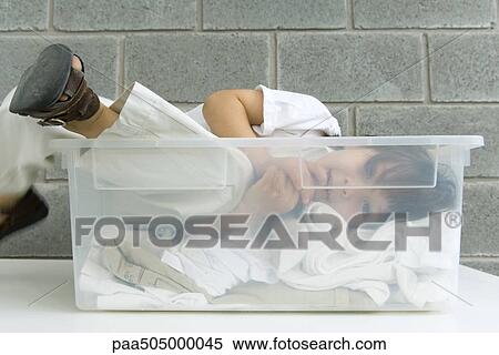 Little boy lying in plastic storage container on top of laundry View Large Photo Image Stock Photography - Little boy lying in plastic storage container on top of laundry. Fotosearch