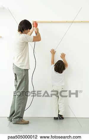 Man drilling into wall, his son reaching up, trying to help View Large Photo Image Stock Image - Man drilling into wall, his son reaching up, trying to help. Fotosearch