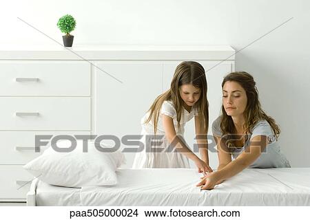 Mother and daughter making bed together View Large Photo Image Picture - Mother and daughter making bed together. Fotosearch
