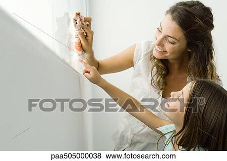Mother cleaning window, daughter pointing out another spot, both smiling View Large Photo Image Stock Photo - Mother cleaning window, daughter pointing out another spot, both smiling. Fotosearch