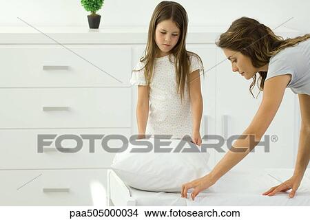 Mother making bed, daughter reluctantly helping View Large Photo Image Picture - Mother making bed, daughter reluctantly helping. Fotosearch