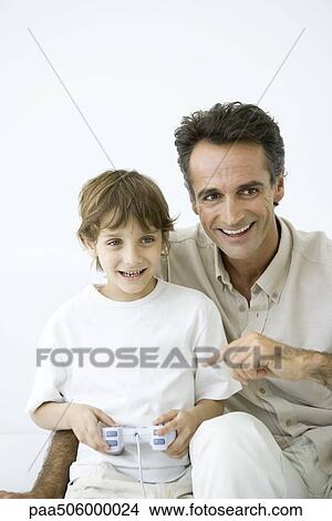 Boy playing video game, father sitting with him, pointing at controller View Large Photo Image Picture - Boy playing video game, father sitting with him, pointing at controller. Fotosearch