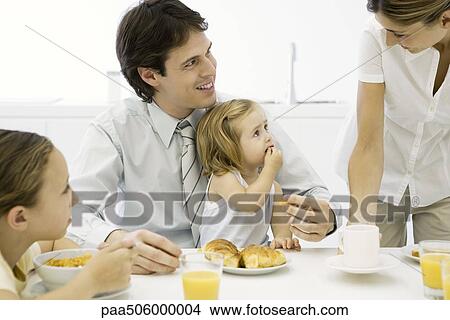 Family around a table, eating breakfast together View Large Photo Image Picture - Family around a table, eating breakfast together. Fotosearch