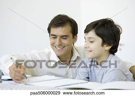 Stock Photo - Father helping his son do homework, both smiling. Fotosearch