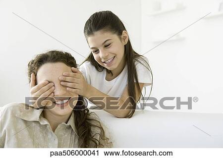 Girl standing with hands over her young woman's eyes, both smiling View Large Photo Image Stock Image - Girl standing with hands over her young woman's eyes, both smiling. Fotosearch