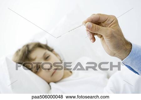 Little boy lying in bed, man's hand holding thermometer in foreground View Large Photo Image Stock Photo - Little boy lying in bed, man's hand holding thermometer in foreground. Fotosearch