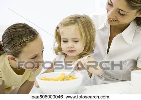 Little girl eating cereal, older sister and mother watching View Large Photo Image Stock Photograph - Little girl eating cereal, older sister and mother watching. Fotosearch
