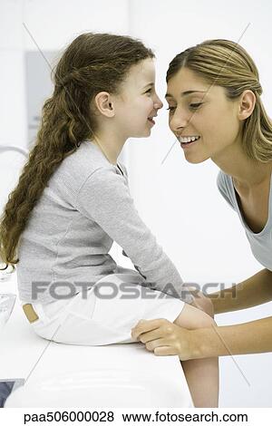 Little girl whispering in her mother's ear, side view View Large Photo Image Stock Photo - Little girl whispering in her mother's ear, side view. Fotosearch