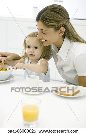 Mother and daughter sitting at table, eating breakfast View Large Photo Image Stock Photography - Mother and daughter sitting at table, eating breakfast. Fotosearch