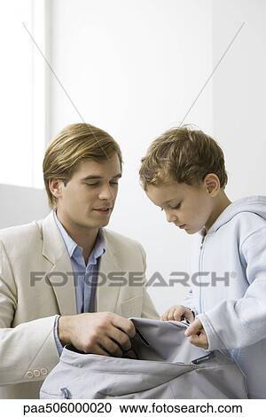 Well-dressed man crouching down, holding backpack together with his son View Large Photo Image Stock Image - Well-dressed man crouching down, holding backpack together with his son. Fotosearch