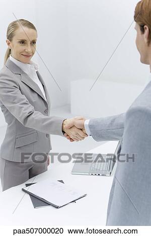 Businesswoman shaking hands with cropped view of red-headed businessman View Large Photo Image Stock Image - Businesswoman shaking hands with cropped view of red-headed businessman. Fotosearch