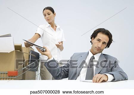 Man handing binder back to assistant, shopping cart full of boxes nearby View Large Photo Image Stock Photo - Man handing binder back to assistant, shopping cart full of boxes nearby. Fotosearch