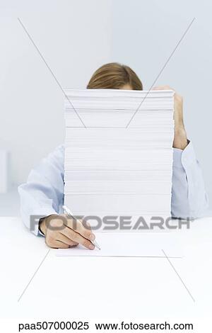 Man hiding behind tall stack of paper, reaching around to write on a single sheet of paper View Large Photo Image Stock Photography - Man hiding behind tall stack of paper, reaching around to write on a single sheet of paper. Fotosearch