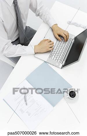 Man using laptop on desk, high angle cropped view View Large Photo Image Stock Photograph - Man using laptop on desk, high angle cropped view. Fotosearch