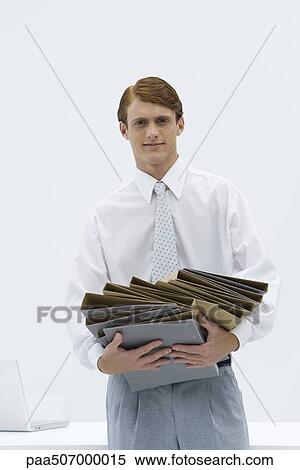 Professional man carrying a disorganized stack of binders, looking at camera View Large Photo Image Stock Photography - Professional man carrying a disorganized stack of binders, looking at camera. Fotosearch