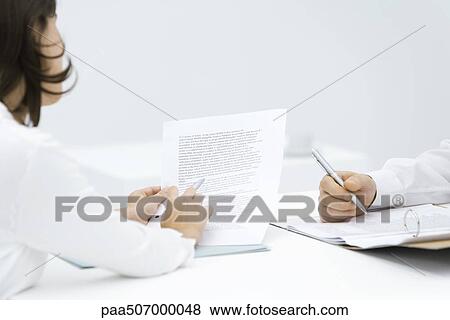Woman scrutinizing contract, man editing document in binder, cropped view View Large Photo Image Stock Photo - Woman scrutinizing contract, man editing document in binder, cropped view. Fotosearch