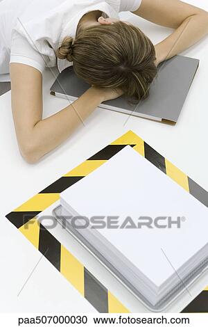 Woman sitting with her head down near a stack of paper surrounded by black and yellow tape View Large Photo Image Stock Image - Woman sitting with her head down near a stack of paper surrounded by black and yellow tape. Fotosearch