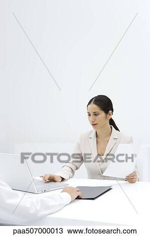 Woman using laptop while holding a document, cropped view of arm pushing folder across desk View Large Photo Image Stock Image - Woman using laptop while holding a document, cropped view of arm pushing folder across desk. Fotosearch