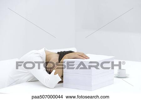 Woman with head down on desk, arm obscuring face, hand on top of stack of paper View Large Photo Image Picture - Woman with head down on desk, arm obscuring face, hand on top of stack of paper. Fotosearch