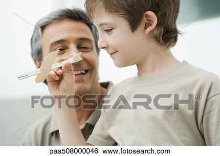 Boy holding toy plane, mature man watching View Large Photo Image Stock Photograph - Boy holding toy plane, mature man watching. Fotosearch