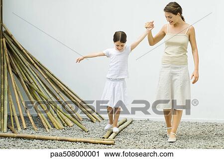 Girl balancing on bamboo, mother helping her by holding her hand View Large Photo Image Stock Image - Girl balancing on bamboo, mother helping her by holding her hand. Fotosearch