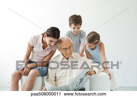 Grandfather reading newspaper, three grandchildren looking over his shoulder View Large Photo Image Stock Image - Grandfather reading newspaper, three grandchildren looking over his shoulder. Fotosearch