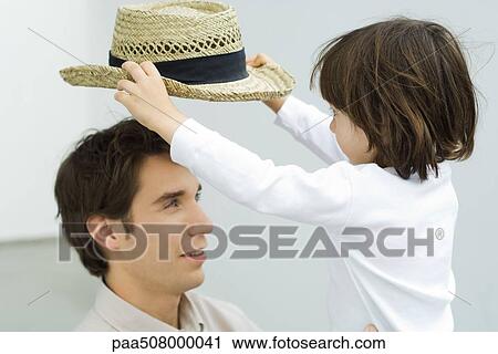 Little boy picking hat up off his father's head View Large Photo Image Stock Image - Little boy picking hat up off his father's head. Fotosearch