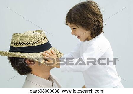 Little boy pulling hat down over his father's eyes View Large Photo Image Stock Photo - Little boy pulling hat down over his father's eyes. Fotosearch