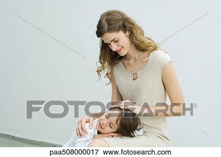 Stock Photo - Little boy resting head on mother's lap, woman stroking child's hair. Fotosearch
