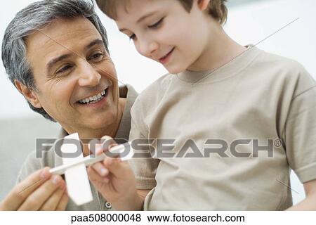 Mature man and boy holding toy plane together View Large Photo Image Stock Photo - Mature man and boy holding toy plane together. Fotosearch